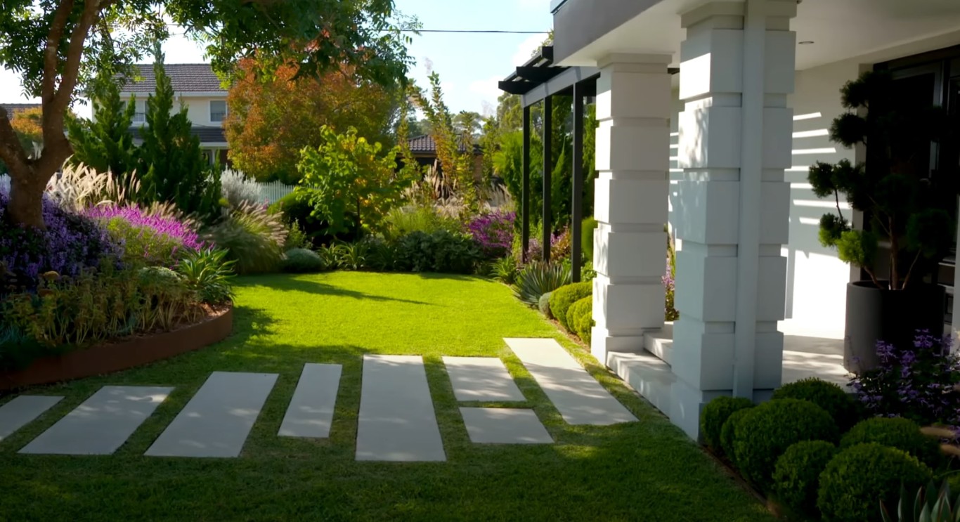 Professional landscape design with white columns and lush flower beds in Brookline, MA