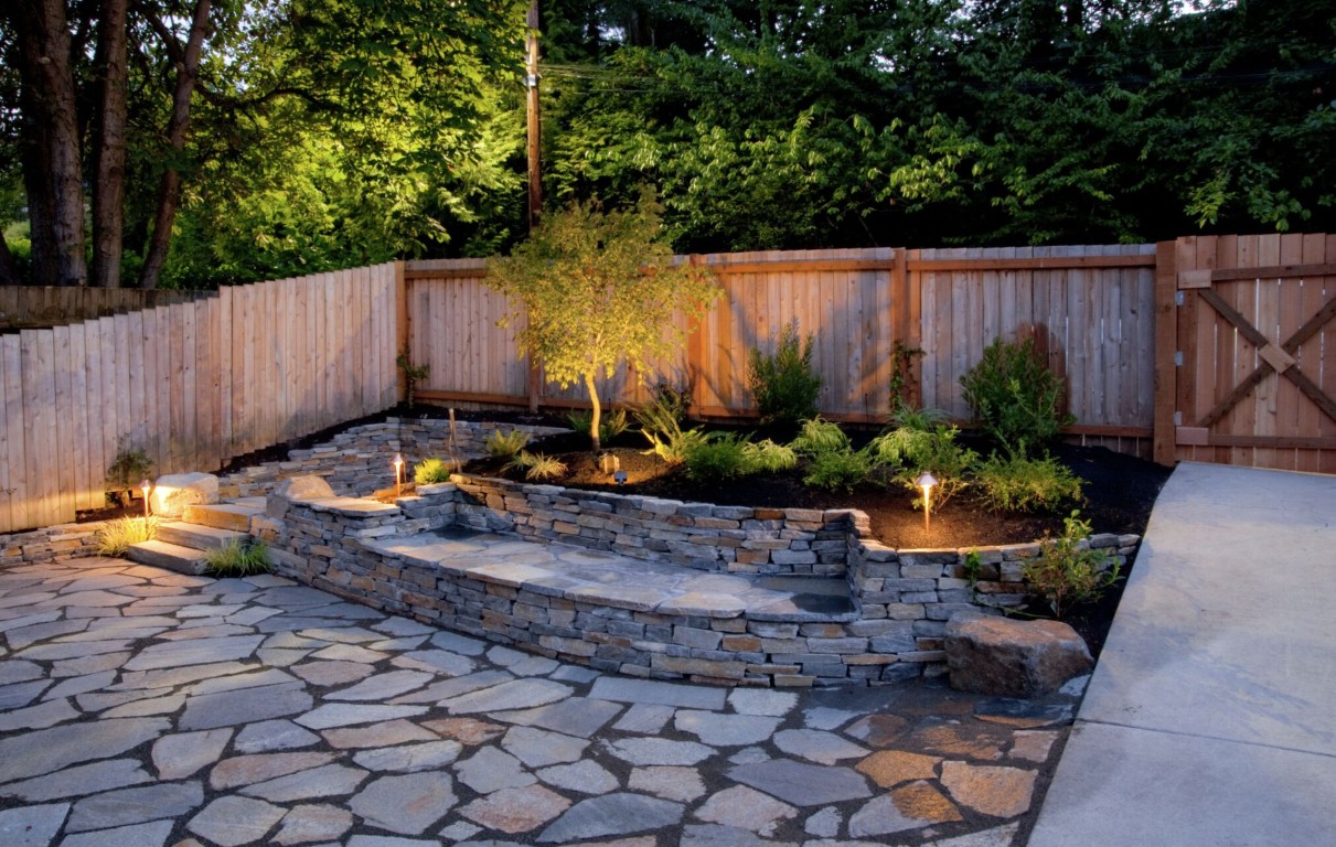 Professional landscape lighting with raised stone walls in Brookline, MA